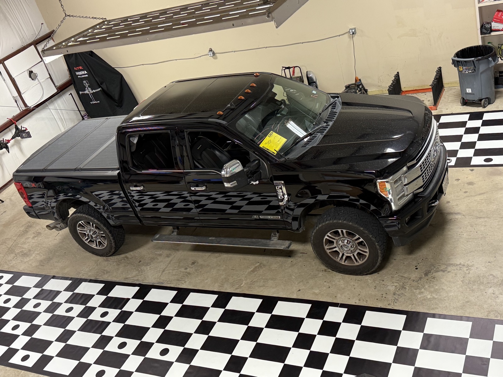 Black Ford F-250 Super Duty in the air-conditioned South Texas Auto Glass bay with the ADAS calibration target banner behind it in Corpus Christi, TX, where calibration is done in-house and verified to spec