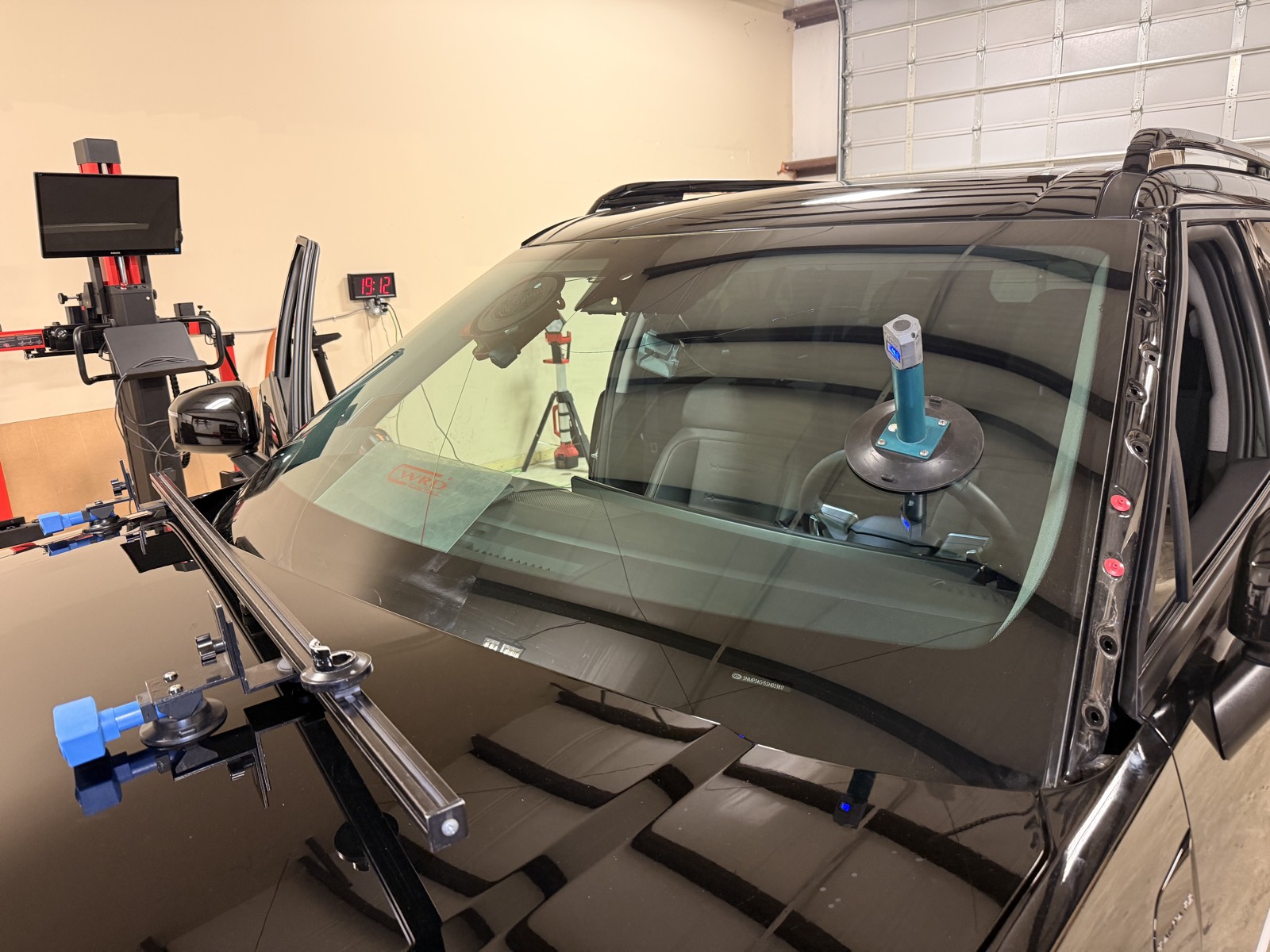 Windshield being set on an SUV with glass-setting tools while an ADAS calibration monitor stands ready in the background, the exact glass work that triggers recalibration, at South Texas Auto Glass in Corpus Christi, TX