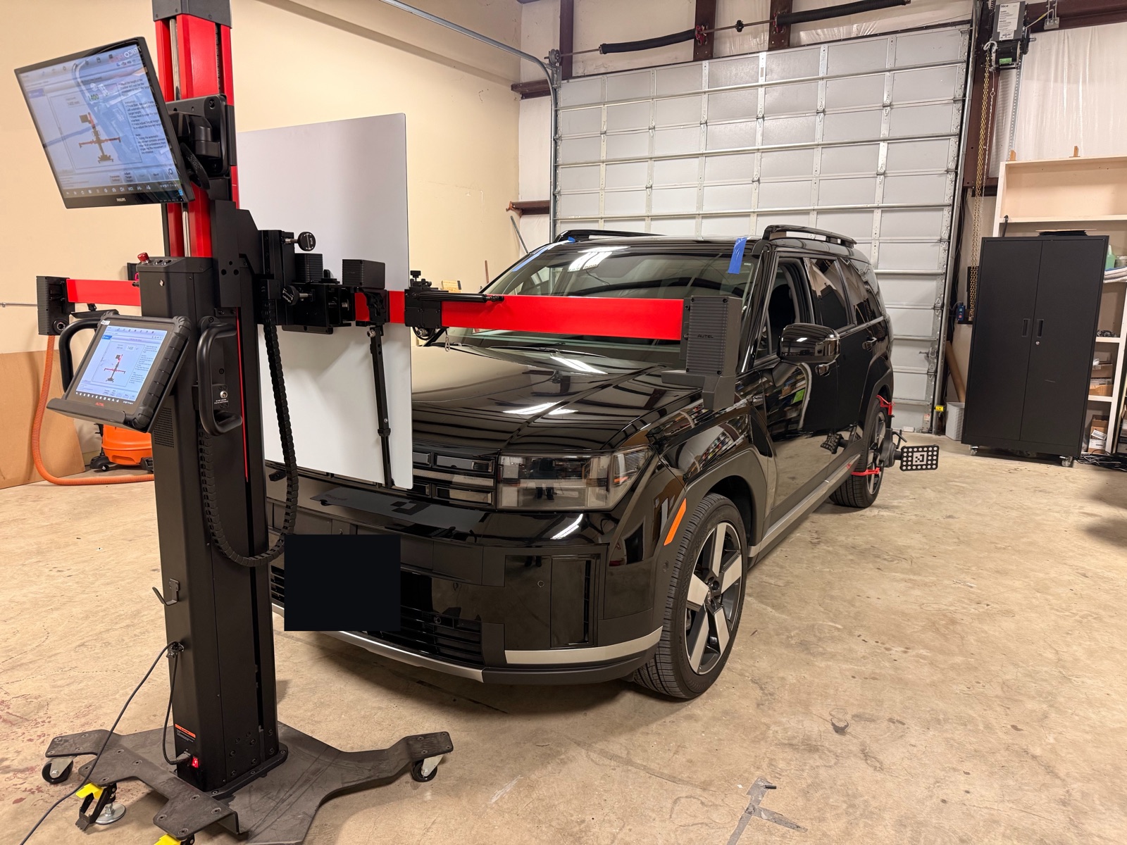 ADAS calibration underway on a black Hyundai Santa Fe — forward-camera calibration rig, target board, and dual monitors inside the South Texas Auto Glass shop in Corpus Christi, TX