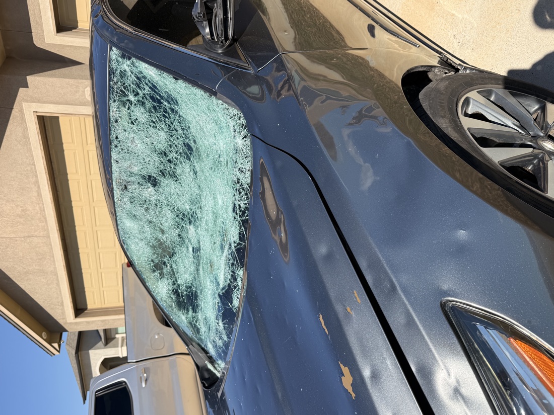 Nissan sedan with a windshield cracked and spidered beyond repair in a Corpus Christi driveway, showing why a small chip should be fixed early
