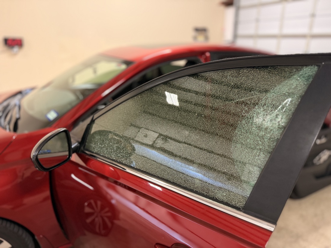 Shattered front door glass on a red coupe waiting for door glass replacement at South Texas Auto Glass in Corpus Christi, TX