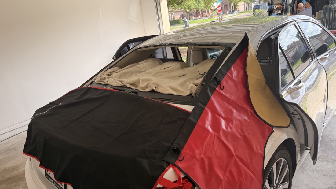 Mercedes-Benz sedan at South Texas Auto Glass in Corpus Christi, TX with its back glass removed and the interior protected under the shop's cover during a quality glass replacement